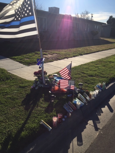 A display of flowers, candles, an American flag, and a cross in front of a residence in Newman. Photo- Steve Newvine