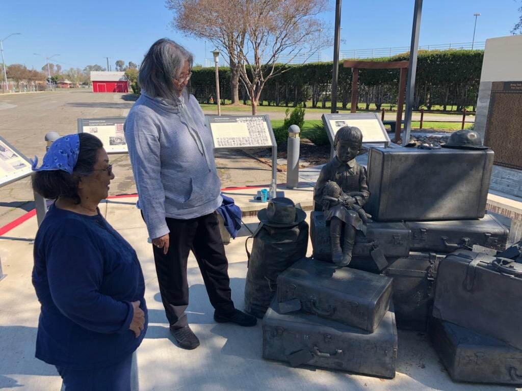 Marlene Tanioka and Patti Kishi view with bronze depiction of a Japanese American family and their belongings as the family is about to be incarcerated at the Merced Internment Memorial. Photo: Steve Newvine